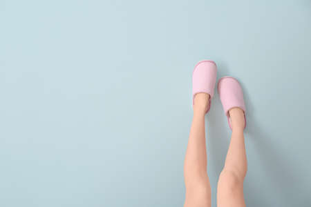Female legs in soft slippers on color backgroundの写真素材