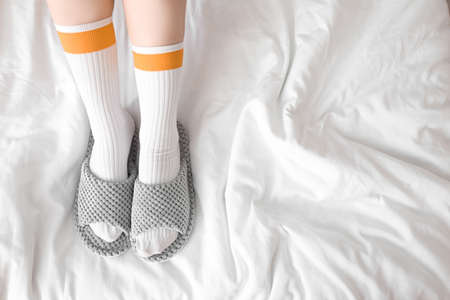 Woman in soft slippers sitting on bedの写真素材