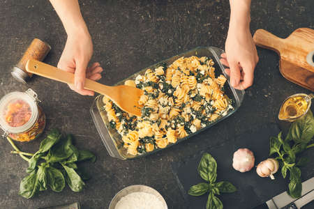 Woman preparing tasty pasta in baking dish on table, top viewの写真素材