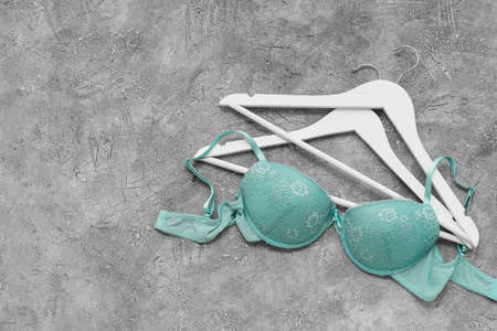 Stylish female bra and hangers on grunge background