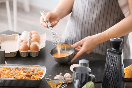 Woman preparing tasty pasta in baking dish on tableの写真素材