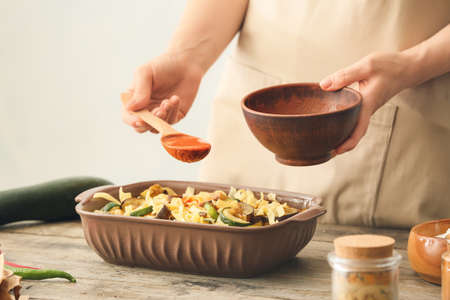 Woman preparing tasty pasta in baking dish on table