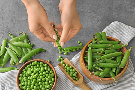 Woman preparing fresh peas on table, top view