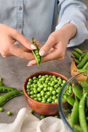 Woman preparing fresh peas on tableの写真素材