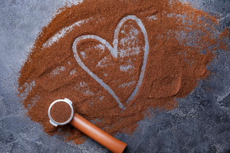 Portafilter with coffee powder and drawn heart on dark backgroundの写真素材