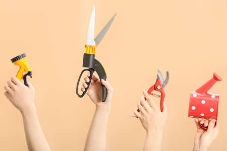 Female hands with gardening tools on color backgroundの写真素材