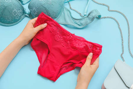 Female hands with stylish lingerie and bag on color backgroundの写真素材