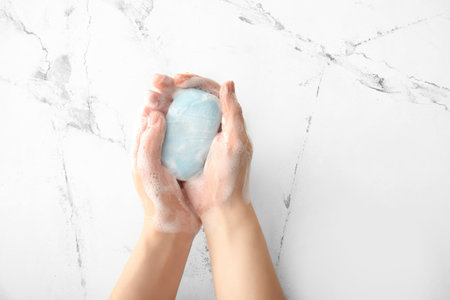 Woman washing hands with soap on white background, top view