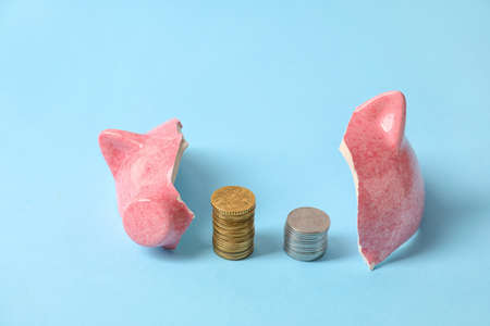 Broken piggy bank and coins on color backgroundの写真素材