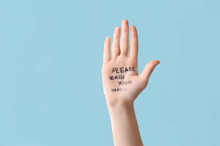 Female hand with written text PLEASE WASH YOUR HANDS on color backgroundの写真素材