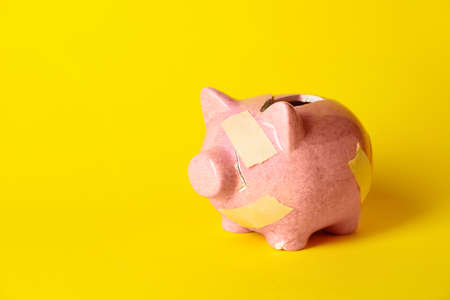 Broken patched piggy bank on color backgroundの写真素材