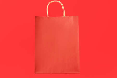 Paper shopping bag on color background