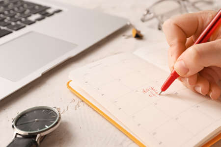 Woman marking day off in calendar at workplace