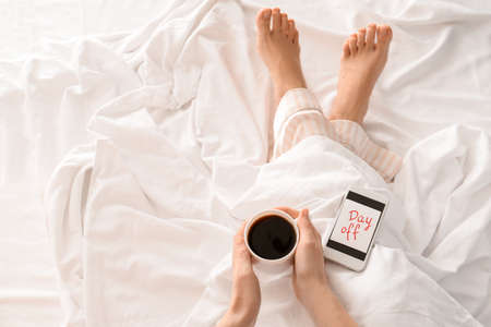 Woman with cup of coffee relaxing in bed. Concept of day offの写真素材