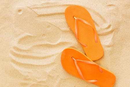 Stylish flip-flops on beach sandの写真素材