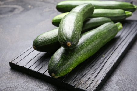 Board with fresh zucchini squashes on dark backgroundの写真素材