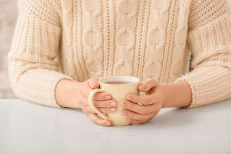 Woman with cup of hot tea at table