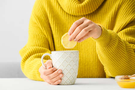 Woman with cup of hot tea at tableの写真素材