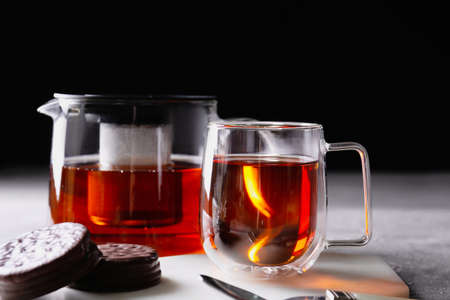 Teapot, cup of hot beverage and cookies on tableの写真素材