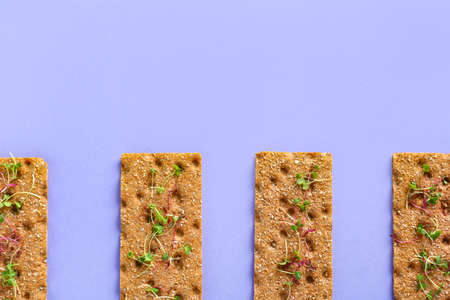 Rye crispbreads with sprouts on color background