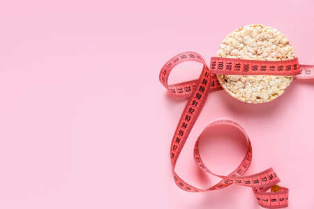 Rice crispbread with measuring tape on color background