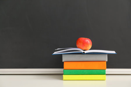 Books with apple on table in classroomの写真素材