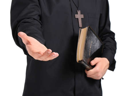 Handsome young priest with Bible on white background, closeup