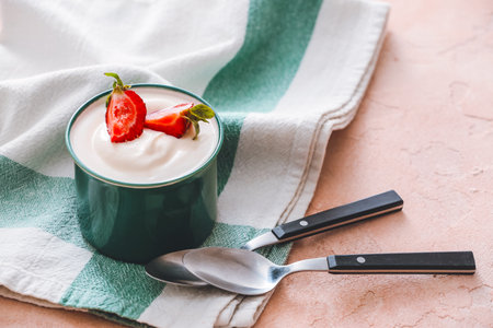 Cup of strawberry yogurt on color background