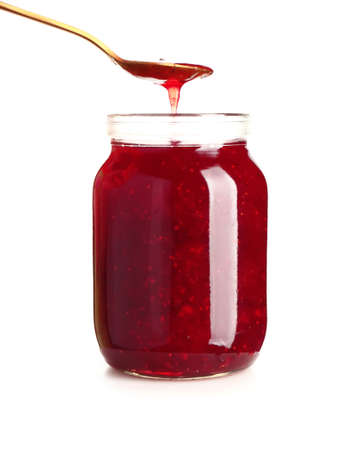 Jar of tasty strawberry jam and spoon on white backgroundの写真素材
