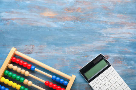 Abacus and calculator on wooden background