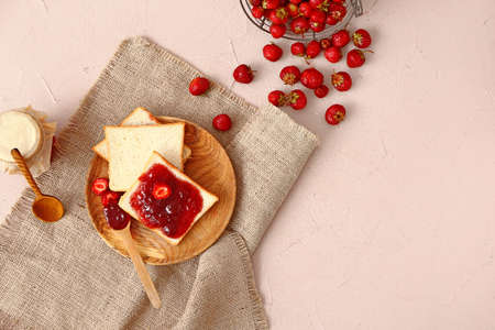 Plate with tasty strawberry jam and bread on color backgroundの写真素材