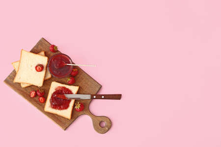 Board with tasty strawberry jam and bread on color backgroundの写真素材