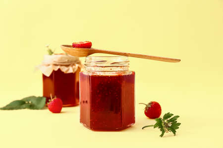 Jar of tasty strawberry jam on color background