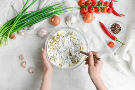 Woman preparing tasty pasta on light background, top view