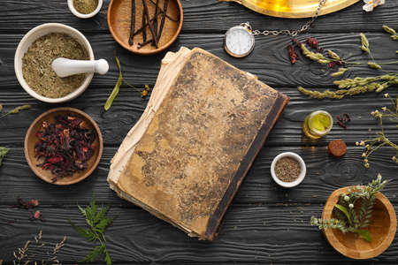 Old book and ingredients for preparing potions on alchemist's tableの写真素材