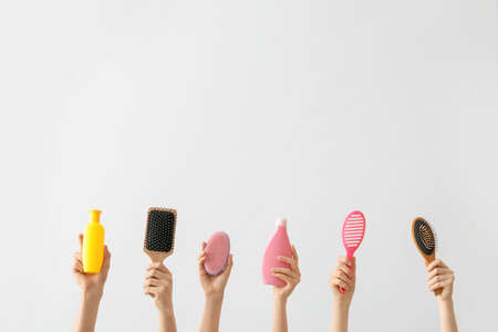Female hands with hair tools on light backgroundの写真素材