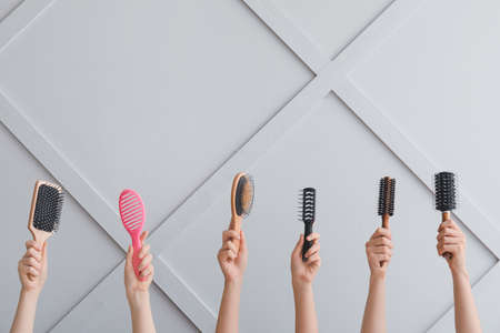 Female hands with hair tools on light background