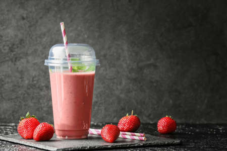 Cup of tasty strawberry smoothie on dark backgroundの写真素材