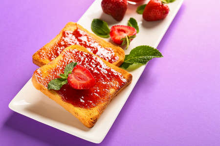 Plate with tasty strawberry jam and bread on color backgroundの写真素材