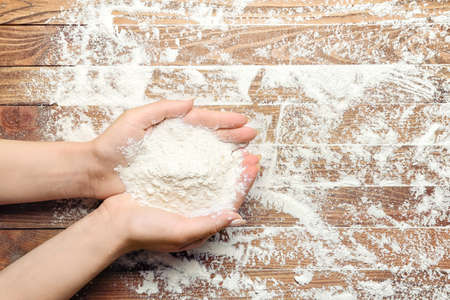 Female hands with rice flour on wooden background