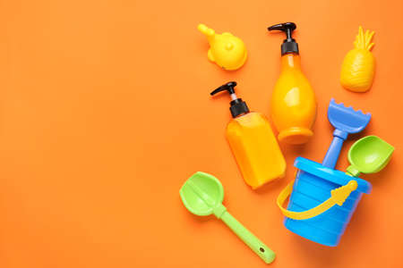 Sunscreen cream with beach sand toys on color background