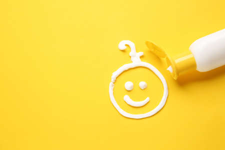 Drawing of baby made with sunscreen cream on color background