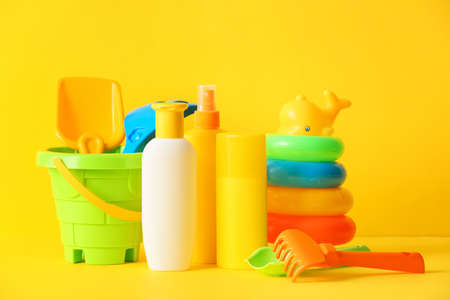 Sunscreen cream with beach sand toys on color backgroundの写真素材