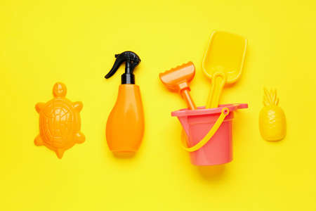 Sunscreen cream with beach sand toys on color backgroundの写真素材