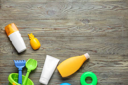 Sunscreen cream with beach sand toys on wooden background
