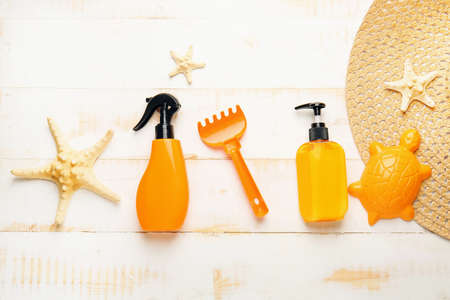 Sunscreen cream with beach sand toys and accessories on wooden background