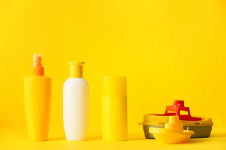 Sunscreen cream with beach sand toys on color backgroundの写真素材
