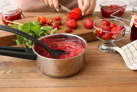 Sweet strawberry jam on table in kitchen