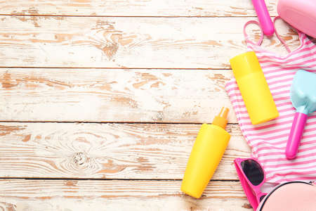Sunscreen cream with beach sand toys and accessories on wooden background