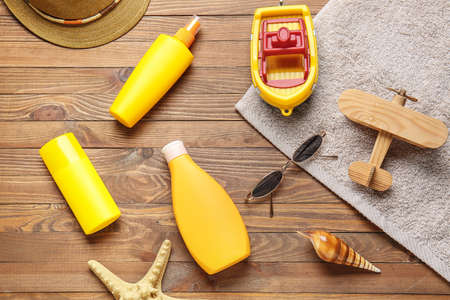 Sunscreen cream with toys and beach accessories on wooden background